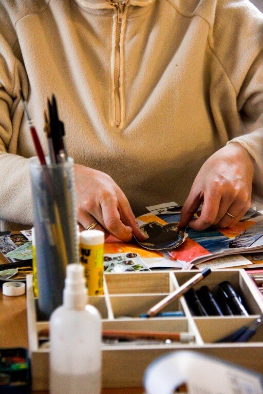 אישה מדביקה על גבי המחברת, חומרי יצירה מסביב