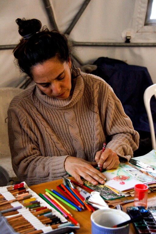 אישה מציירת בסטודיו על גבי מחברת